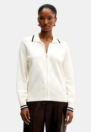 Cardigan bianco con zip, caratterizzato da un motivo floreale testurizzato e orlo a coste. Presenta dettagli neri sul colletto e sui polsini.