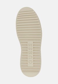 Soletta in gomma crema con scanalature orizzontali e una sezione rettangolare impressa con il logo "GUESS".