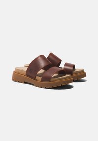 Sandali a infradito in pelle marrone con due cinturini larghi, un plantare imbottito e una suola in gomma resistente con un motivo a trama testurizzata.