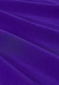 Lila texturerad tyg med en slät yta, som har jämna veck och ett stickat mönster, vilket skapar ett strukturerat, flödande utseende.