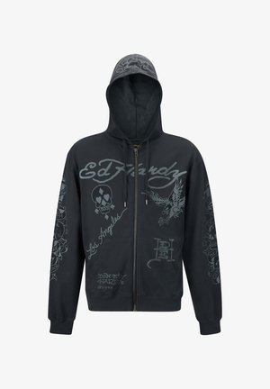 Felpa nera con zip, caratterizzata da grafiche grigie, tra cui un teschio, un'aquila e un logo in stile scrittura. Ha un cappuccio, tasche frontali e polsini a coste.