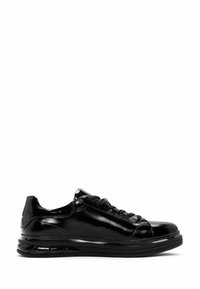 Zapatillas de charol negro con punta redondeada, cordones planos y una suela gruesa y texturizada con líneas horizontales.