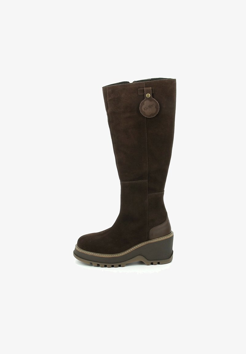Botte haute jusqu'au genou en daim marron foncé avec talon compensé, bout rond, semelle crantée et étiquette circulaire en cuir attachée près du bord supérieur.
