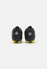Crampons de football noirs avec tige en mesh texturé et synthétique, dotés de crampons jaunes et de logos blancs circulaires sur les talons.