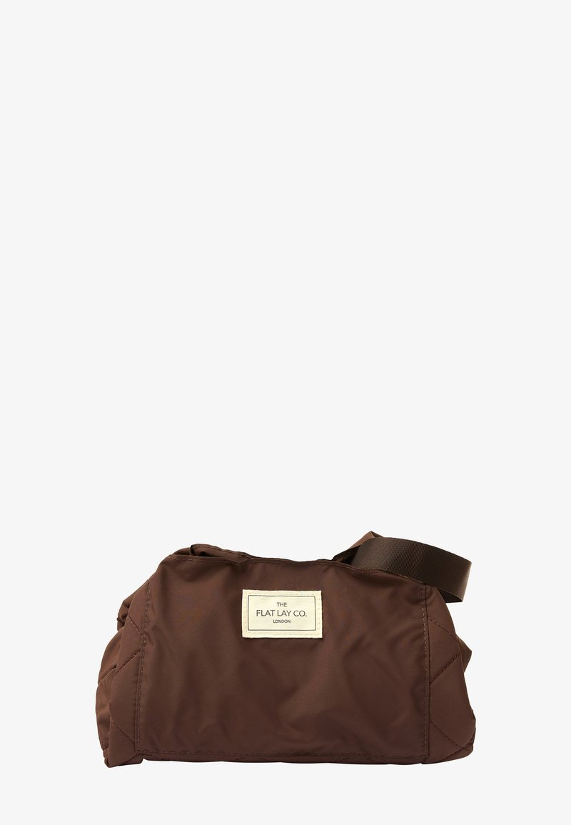 Brun nylon taske med en quiltet tekstur, der har en stofrem og et rektangulært varemærke på den ene side. Kompakt, afrundet design.