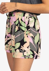 Pantaloni corti con stampa floreale e cintura elastica, caratterizzati da foglie verdi, rosa e nere. Realizzati in tessuto leggero, adatti per un abbigliamento casual.