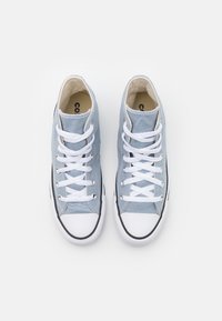 Zapatillas altas de lona azul claro con puntera y suela de goma blanca, con cordones blancos y acentos negros en la suela.