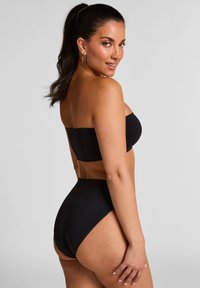 Zwarte bandeau top gecombineerd met hoge taille zwarte bikini bottoms. Glad, rekbaar materiaal met minimale naden en een strakke uitstraling.