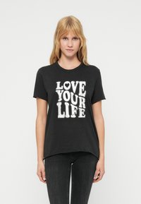 Μαύρο βαμβακερό t-shirt με κοντά μανίκια, που φέρει ένα μεγάλο λευκό γραφικό τύπωμα με τη φράση «LOVE YOUR LIFE» σε στιλιζαρισμένα γράμματα.