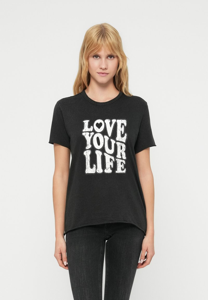 Μαύρο βαμβακερό t-shirt με κοντά μανίκια, που φέρει ένα μεγάλο λευκό γραφικό τύπωμα με τη φράση «LOVE YOUR LIFE» σε στιλιζαρισμένα γράμματα.