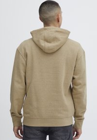 Hoodie beige in misto cotone, con cappuccio regolabile, polsini a costina e vestibilità rilassata. Texture liscia senza motivi visibili.