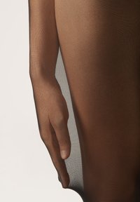 Svart, genomskinlig tyg hänger över en hand och visar en len, genomskinlig textur med subtil lyster. Konturen av handen är synlig.