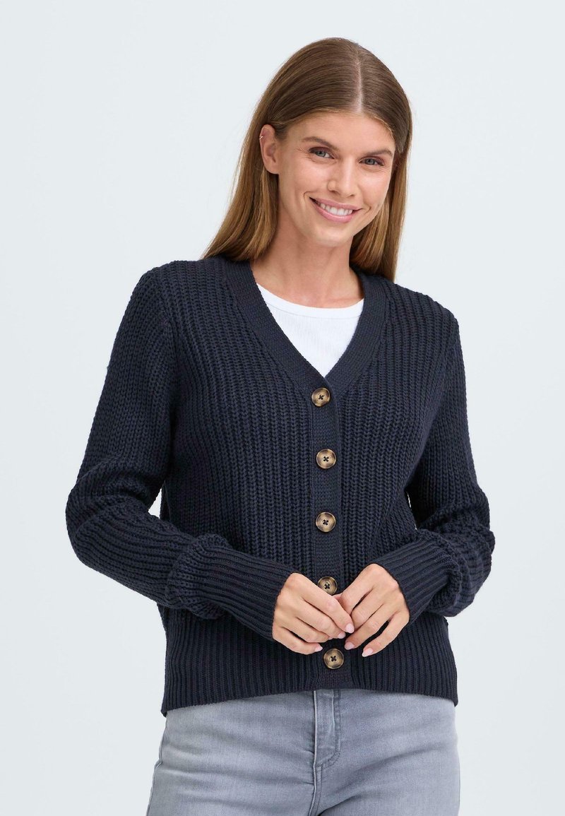 Cardigan tricoté marine avec un décolleté en V, comportant six boutons en bois et des poignets côtelés. Le tissu a une apparence texturée et épaisse.