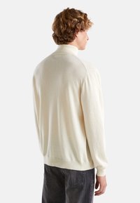 Pull crème avec un col haut, des poignets et un ourlet côtelés. Fabriqué en matériau tricoté doux, avec une coupe décontractée et un design simple.