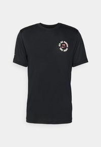 Camiseta de manga corta negra hecha de material suave; presenta un gráfico frontal con una cara sonriente y texto en blanco y rojo. Logo de Nike en la manga.