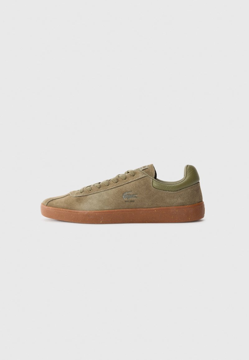 Olive suede sneaker with a gum rubber sole, round toe, flat laces, and a logo accent on the side. Simple, low-top design.