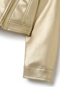 Ärmel einer goldfarbenen Kunstlederjacke mit einer glatten, leicht strukturierten Oberfläche und einem Reißverschlussdetail am Bündchen, das das maßgeschneiderte Design hervorhebt.