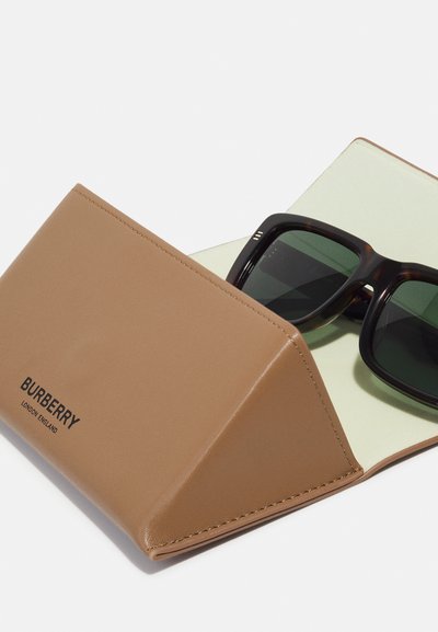 Custodia per occhiali in pelle marrone con interni verde chiaro, dotata di logo Burberry. Gli occhiali da sole in tartaruga scura sono parzialmente visibili all'interno.