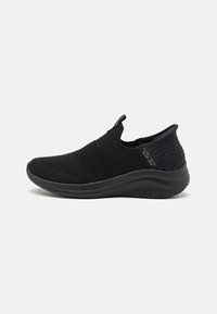 Svart slip-on sneakers laget av mesh-stoff med en teksturert design, rund tå, trekksløyfe og polstret såle.