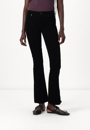 Vaqueros negros de campana hechos de una tela suave, con una cintura de altura media y detalles de costura sutiles. Combinados con zapatos planos negros.