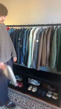 Klädhängare med olika ytterkläder i olika färger, material och texturer. Nedanför, en hylla som visar flera par sneakers.