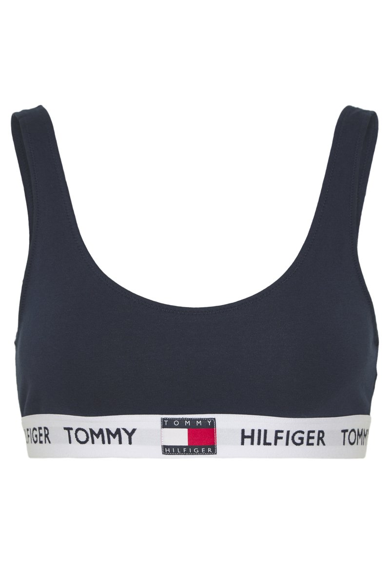 Sujeta deportivo navy con tirantes anchos, escote en forma de copa y una banda contrastante blanca en la cintura que presenta el logo "TOMMY HILFIGER" y un detalle de bloques de color.