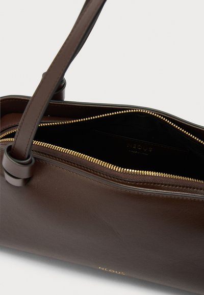 Σκούρα καφέ δερμάτινη τσάντα χειρός με χρυσλό φερμουάρ μερικώς ανοιχτό, που αποκαλύπτει μαύρο εσωτερικό και έναν μονό ιμάντα ώμου.