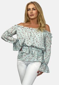 Jasnoniebieska bluzka bez ramiączek z kwiecistym wzorem, z falbaną na dekolcie i rękawach, z wcięciem w talii i warstwowym krojem.