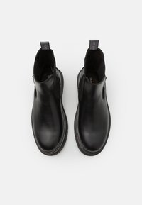 Bottes basses en cuir noir avec panneaux élastiques sur les côtés, languette d"aide au chaussage et bout arrondi. Les semelles sont épaisses et texturées pour une bonne adhérence.