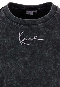 Black crew-neck t-shirt with a textured finish, featuring white embroidered logo on the chest. Ribbed neckline adds detail.
