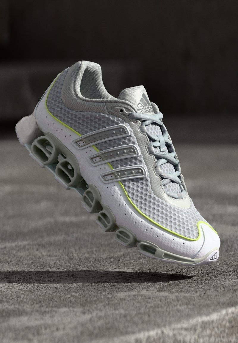 Adidas tekače čevlje s kombinacijo bež in sivo mrežasto zgornjico, neon rumenimi detajli, šestimi podložnimi odprtinami in sivimi vezalkami.