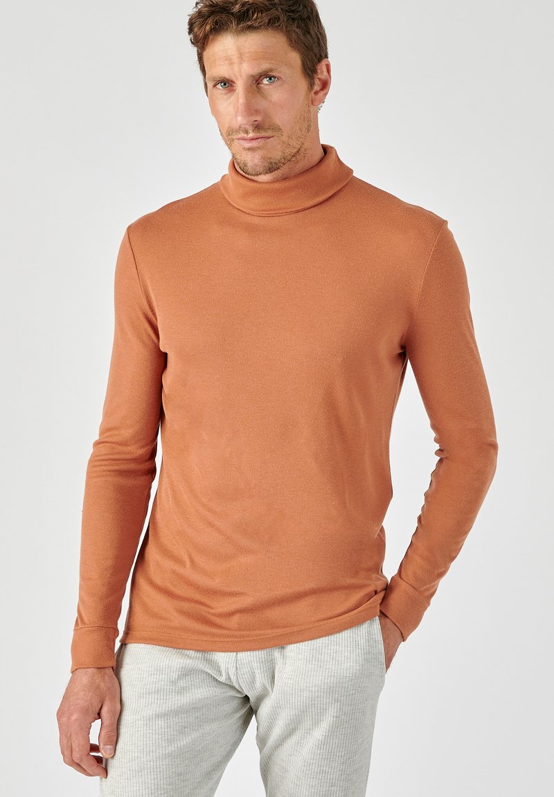 Langarm turtleneck in roestoranje, gemaakt van zacht materiaal. Heeft een aansluitend ontwerp en subtiele ribbels langs de kraag en manchetten.