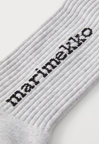 Szürke bordázott zoknik, fekete hímzett "marimekko" logóval. Az anyag lágy hatásúnak tűnik, texturált felülettel.