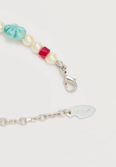 Κούμπωμα ασημένιου κολιέ με μαργαριτάρι, κόκκινες και τιρκουάζ χάντρες, και μια αλυσίδα με ταμπέλα χαραγμένη με "Off-White™" σε λευκό φόντο.