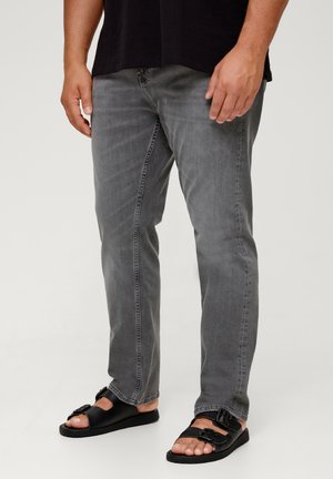 Grijze spijkerbroek met een slim fit en subtiele wassing, gecombineerd met zwarte platte sandalen met dubbele gespen en open teenvorm.