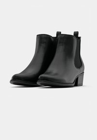 Botines de cuero negro con acabado liso, punta redondeada, paneles laterales elásticos y tacón bajo tipo bloque. Diseño minimalista sin adornos.