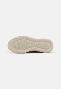 Suela de zapato en goma de color beige claro con una superficie texturizada que presenta un patrón en cuadrícula y una inscripción de la marca, proporcionando tracción y durabilidad.