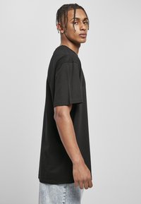T-shirt noir à manches courtes en coton, avec un col rond et une coupe décontractée. Porté avec un jean en denim bleu clair.