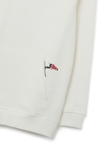 Sudadera blanca con un pequeño diseño bordado de un esquiador en rojo y negro. Incluye un bolsillo delantero y puños y dobladillo acanalados.