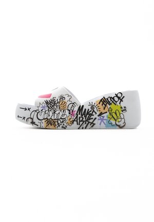 White slip-on clogs with a textured rubber sole, featuring colorful graffiti patterns and designs on the upper for a playful look.