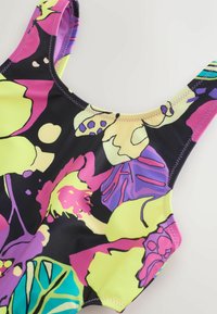 Farverig badedragt i én del med sort bund og et blomstermotiv i gul, pink, lilla og grøn. Glat, strækbart stof med smalle stropper.