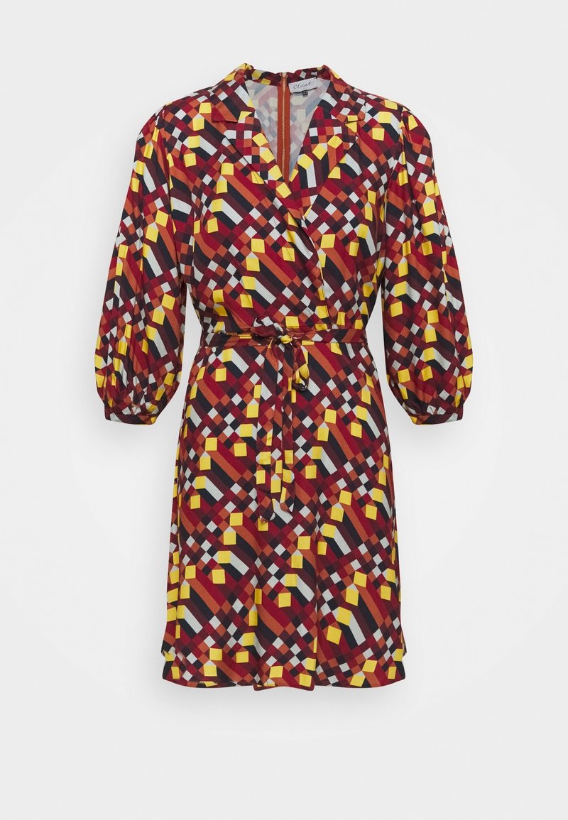 Robe courte avec un motif géométrique audacieux en rouge, jaune et noir. Des manches ballon et une ceinture à nouer embellissent le design.