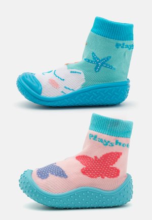 Calçado de cores vivas com uma sola texturizada em turquesa e tecido estampado. Um sapato tem um design de estrela-do-mar, enquanto o outro tem borboletas.