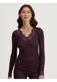 Langsleeve top in diep paars geribbeld stof met een V-hals met kantafwerking en kanten accenten bij de uiteinden.