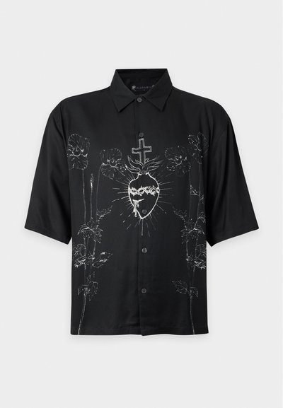 Chemise noire à manches courtes avec boutons, avec un graphisme blanc d'un cœur sacré et des motifs floraux sur le devant.