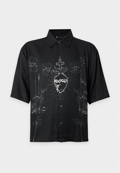 Chemise noire à manches courtes avec boutons, avec un graphisme blanc d'un cœur sacré et des motifs floraux sur le devant.