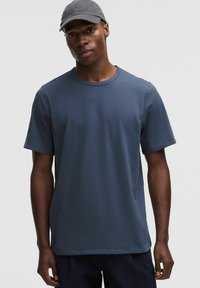 T-shirt en coton bleu marine avec un col rond et des manches courtes. Texture lisse et coupe décontractée, accompagné d'une casquette grise.