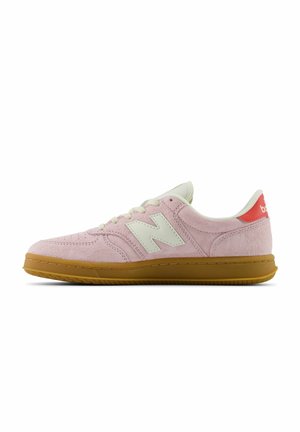 Niedriger rosa Wildleder-Sneaker mit weißen Schnürsenkeln, weißem "N" Logo, rotem Fersenlasche und brauner Gummisohle, seitlich gezeigt.
