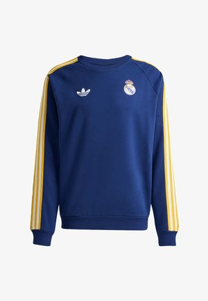 Sweatshirt bleu à manches longues et col rond avec des rayures jaunes et blanches sur les manches, logo Adidas sur le côté gauche de la poitrine et écusson du Real Madrid sur le côté droit.