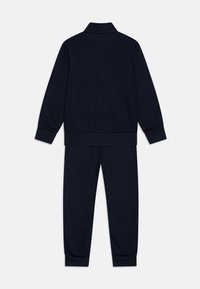 Marineblauwe trainingsoutfit van zachte stof. Heeft een ritskraag en geribbelde manchetten. Inclusief bijpassende broek met elastische tailleband.